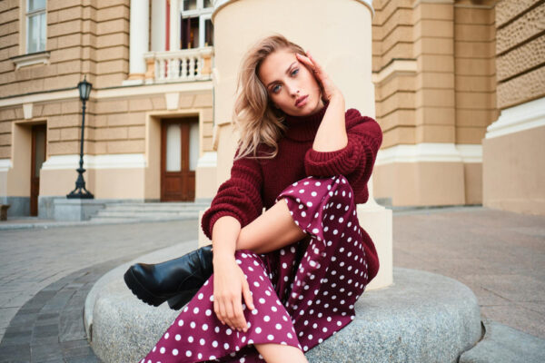 Femeie cu fustă cu buline, așezată în decor urban elegant