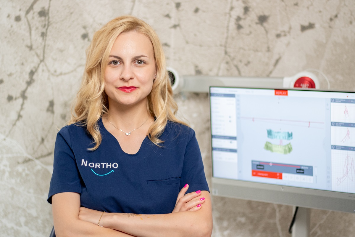 Medic ortodont în clinică, lângă monitor dentar